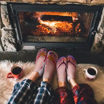 Luxurious Women's Novelty Gift Super Comfy Manicure Print Socks displayed beside a glowing fireplace, creating a cozy ambiance with coffee cups.
