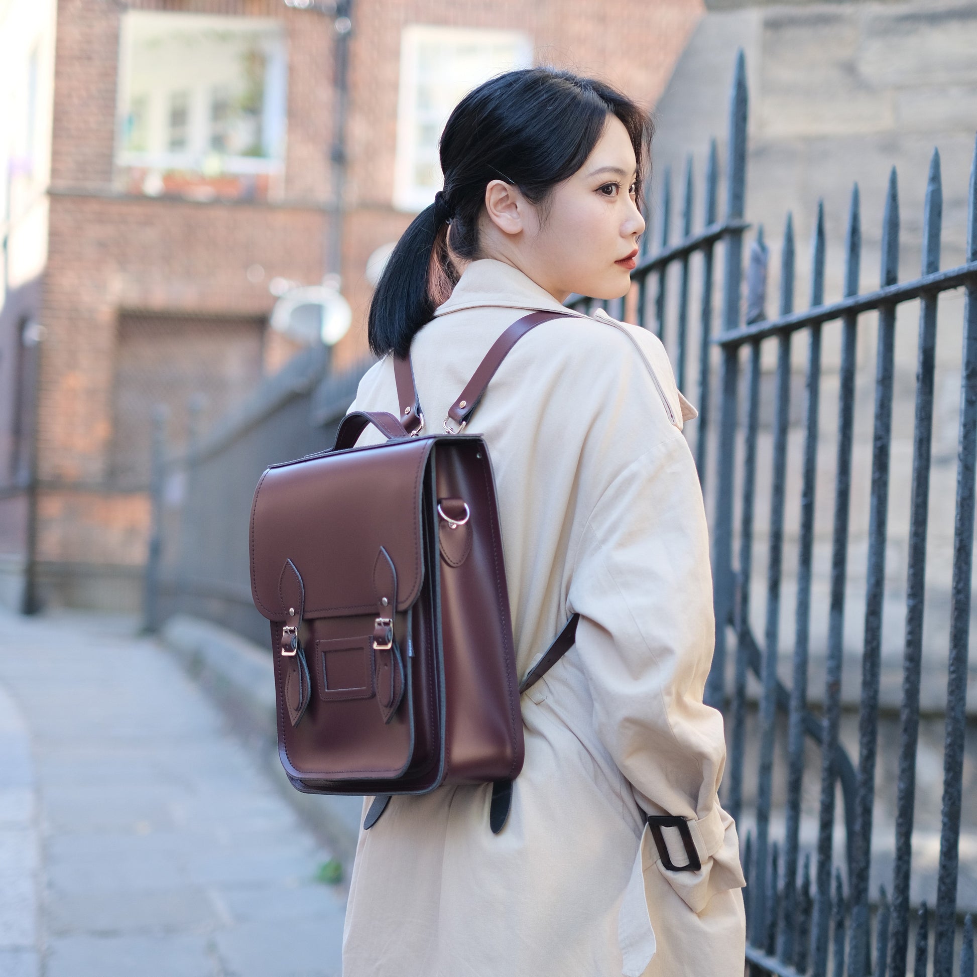 Stylish model showcasing the Handmade Marsala Red Leather City Backpack in an urban setting, embodying luxury and practicality.