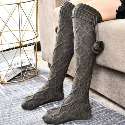 Luxury Women's Warm Winter Knitted Socks - Cozy, Cute, and Stylish Footwear for Every Occasion, featuring a model showcasing grey knitted socks with pom pom details while sitting comfortably on a stylish sofa.
