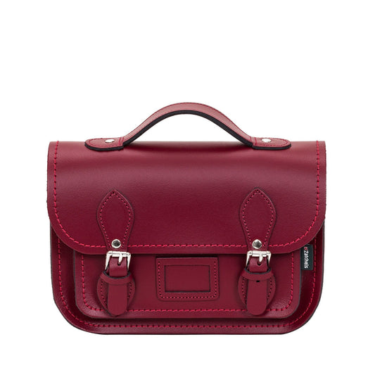 Oxblood leather midi satchel handcrafted in England, showcasing its stylish design with adjustable strap and nickel silver buckles.