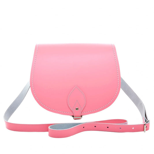 Elegant luxury handmade leather saddle bag in pastel pink with adjustable crossbody strap, showcasing exceptional craftsmanship and timeless design.
