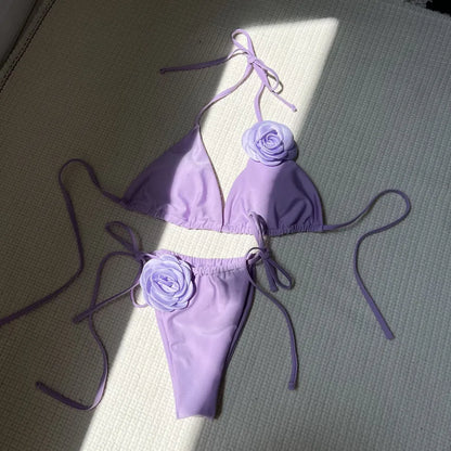 Chic women's bikini set displayed on a sunlit beach, demonstrating the stylish low waist design and vibrant flower pattern.