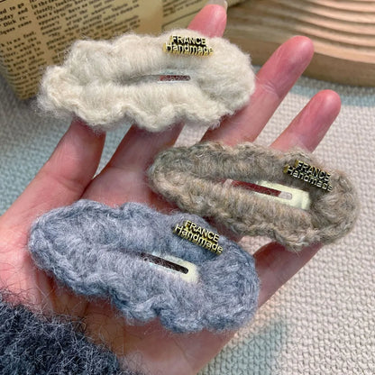 Elegant plush lamb fur hair clip in soft cream colour, perfect for high-end fashion looks styling.