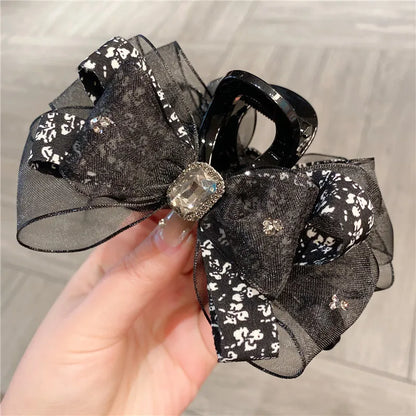 A beautifully styled woman wearing the floral silk shark clip with a butterfly knot, highlighting its sophisticated and pastoral aesthetic.