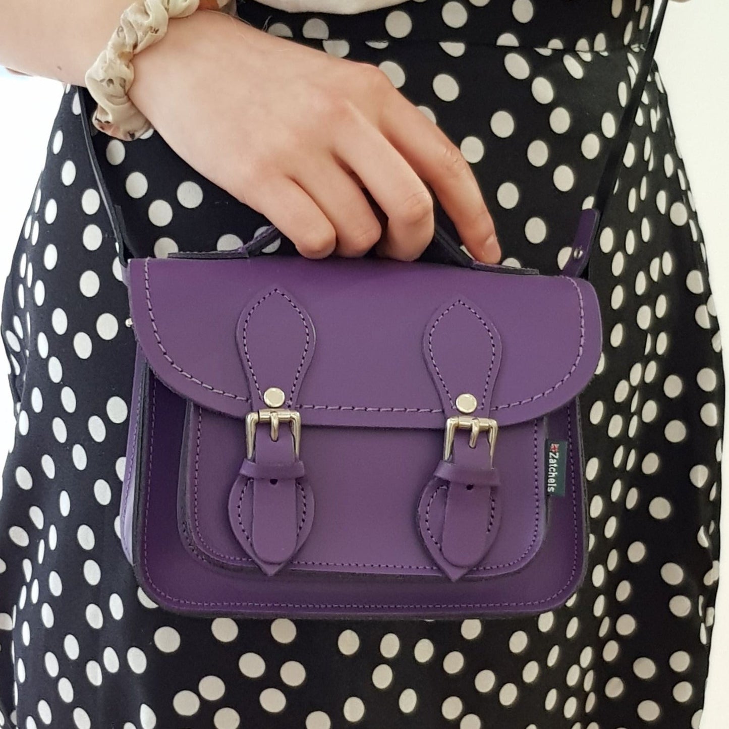 Close-up view of the stunning purple leather micro satchel showcasing exquisite stitching and nickel silver buckles, embodying luxury and style.