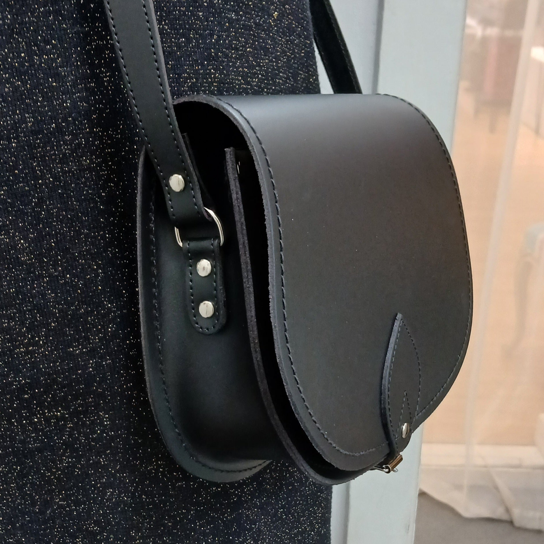 Handcrafted black leather saddle bag by Zatchels, showcasing classic design with adjustable strap, exquisite craftsmanship, and spacious interior for essentials.