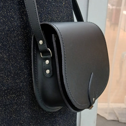 Handcrafted black leather saddle bag by Zatchels, showcasing classic design with adjustable strap, exquisite craftsmanship, and spacious interior for essentials.