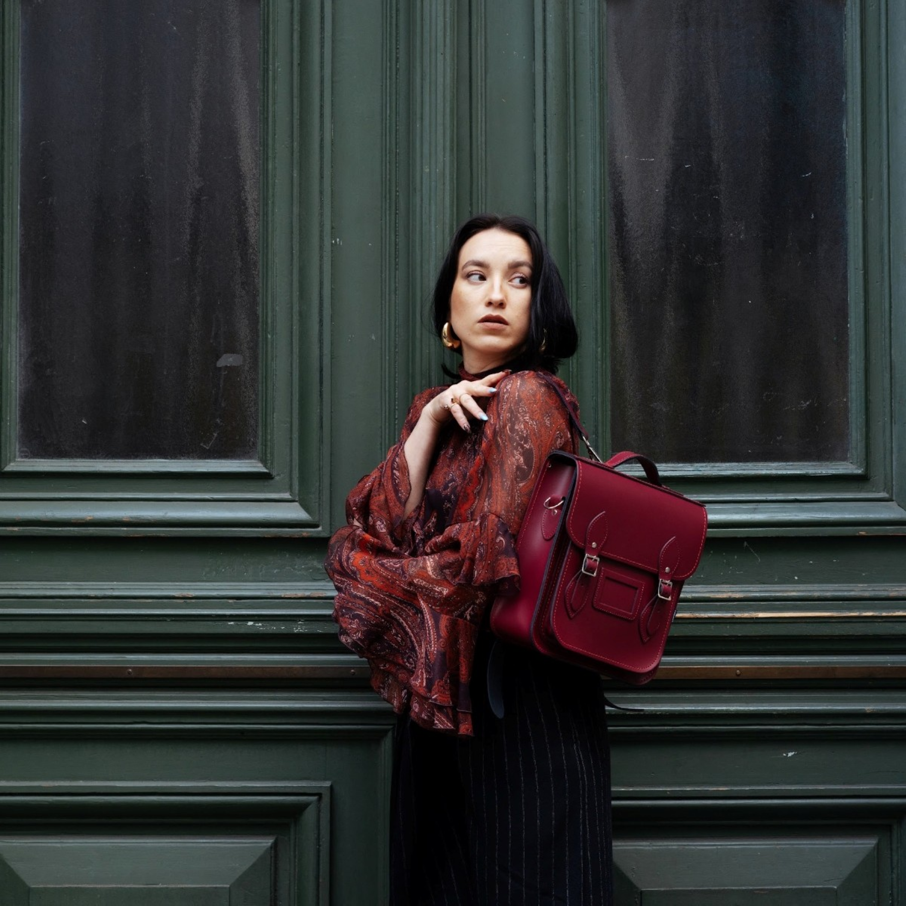 Close-up of exquisite stitching and silver nickel buckles on luxury handmade Oxblood leather backpack, highlighting sophisticated details.
