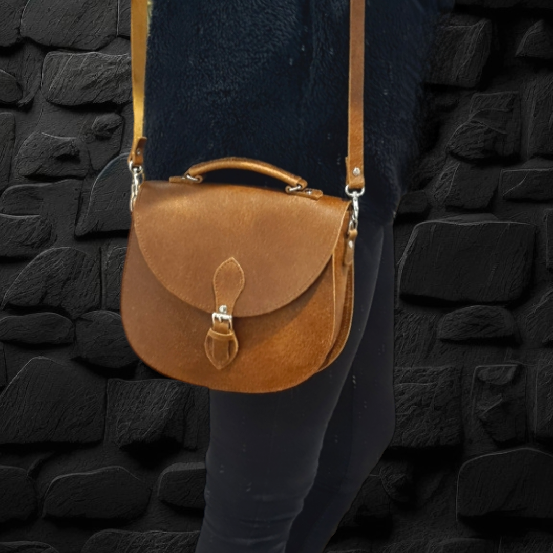 Handmade Tan Tannery Leather Saddle Bag against a chic backdrop, capturing the timeless elegance and unique character developed over time.