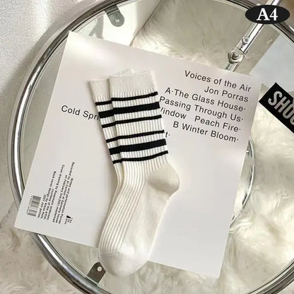 Elegant Women's Tie-Dye Middle Tube Socks with bold black stripes on a pristine white background, presented on a modern surface to emphasise vibrant comfort for all-day style.
