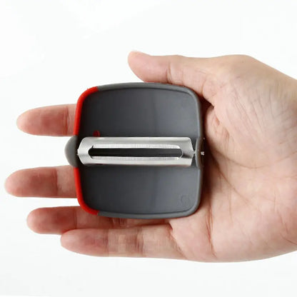 Hand-held ergonomic peeler with stainless steel blade, featuring a sophisticated grey and red design, ideal for effortless food preparation and comfort in the kitchen.