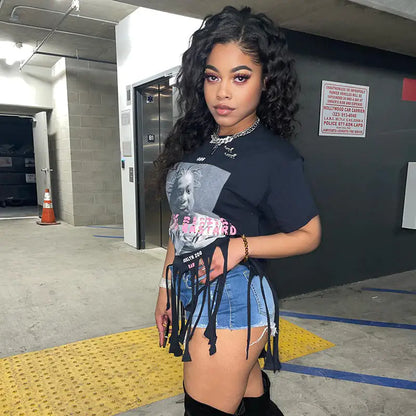 Elegant shot of a model in the Women's ODB Graphic Print Tassel Tee with Stretchy Fabric for Chic Street Style, highlighting the unique graphic design and tassel details, set against a contemporary urban background.