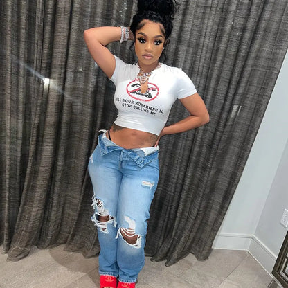 Fashion-forward individual showcasing the Tell Your Boyfriend to Stop Calling Me Slogan Print White Graphic Crop Top, elegantly styled with ripped denim, symbolising modern luxury.