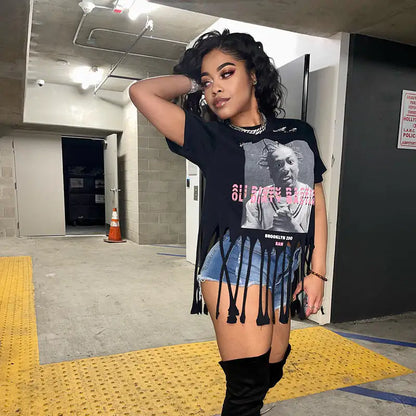 Fashion-forward model showcasing the Women's ODB Graphic Print Tassel Tee with Stretchy Fabric for Chic Street Style, posing confidently with a playful hand on her hair, demonstrating the tee's urban chic essence.