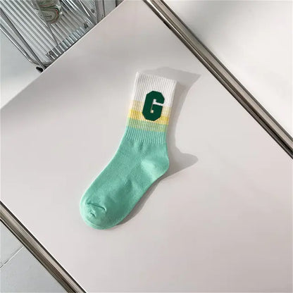 Luxurious Women's Tie-Dye Middle Tube Socks in refreshing green and yellow tones, adorned with a bold letter 'G', perfect for vibrant fashion statements.